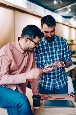 İki mele çalışanı, birbirleri ile ofisinde konuşmak smartphone için yeni app kontrol harcama hipster çocuklar break iş iletişim ve ve komik video fro modern telefon ağ izleme