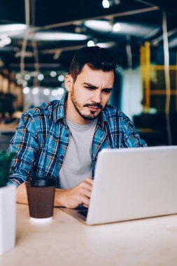 Yorgun genç erkek öğrenci üniversite sınavlarına hazırlanıyor dizüstü bilgisayar netbook düşünme overworked üzgün freelancer okuma bilgileri problem çözümü hakkında sıkıcı webinar izlerken