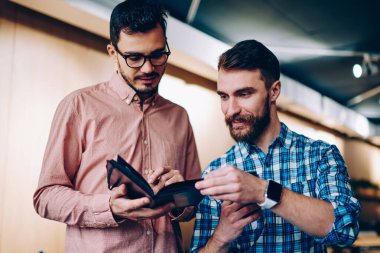 Bilgi için proje, olumlu hipster erkekler birlikte office coworking fikirler tartışırken Not defteri planından öğrenme hakkında konuşmayı okuma birbirleriyle konuşan genç erkek arkadaşları