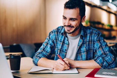 Dizüstü bilgisayarda dizayn etme ve bilgi toplama konusunda eğitim gören genç ve pozitif bir erkek öğrenci. Kafede internet üzerinden dil öğrenmeyi seven zeki hippi.