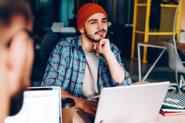 Hayalperest hippi adam çalışma sürecinden uzaklaştırıcı bir şey hayal et. Ofis programcılığında iş arkadaşıyla otururken tatilde olduğunu düşünen düşünceli, olumlu bir adamın görüntüsü.