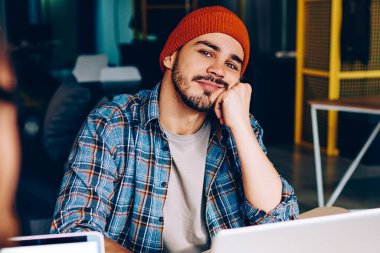 Üniversitede öğrenmek için dizüstü bilgisayarın başına oturmuş kameraya bakan düşünceli hippi adam. İş sırasında iş arkadaşlarıyla bir şeyler hayal eden bir erkeğin kırpılmış görüntüsü.