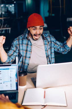 Coşkulu erkek futbol fanatiği takım maçının zaferine hayret ediyor. Çalışma sürecinde çığlık atıyor ve neşeleniyor. Duygusal hipster adam yarışmada kazanmanın harika haberlerini kutluyor.