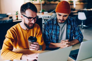 Genç erkek arkadaşlar dizüstü bilgisayarda ödev yapmak için özel ders izliyorlar, pozitif hipster çocuklar birlikte proje üzerinde çalışıyorlar netbook 'taki ağlardan bilgi okuyorlar.