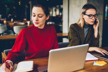 İki yetenekli grafik tasarımcıları uzaktan modern netbooks çalışma coworking kablosuz internet bağlı. Sarışın öğrenci smartphone metin içinde not etmek--dan website belirterek meslektaşım süre: çağrı