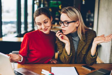 İki şüpheci yetenekli öğrenciler dizüstü bilgisayarda internet sitesinde tasarım tutorial online izlerken bilgi analiz ve tartışmak için kablosuz 4 g bağlı oturma alanı coworking internet