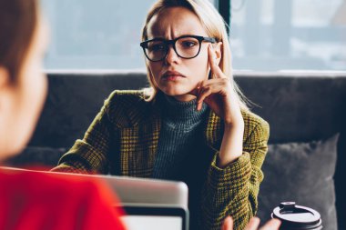 Kadın girişimci dikkatle iş toplantı ve modern dizüstü bilgisayarlar mesafe iş sırasında meslektaşım dinleme konsantre. Üretken strateji tartışmaya Eyewear dalgın genç kadın