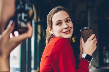 Lezzetli kafein içecek poz ve odaklanan ve coworking boş zamanlarında vintage kamerada fotoğraf yapma yetenekli kadın Amatör süre gülümseyerek elinde olan neşeli kadın üzerinde seçici odak