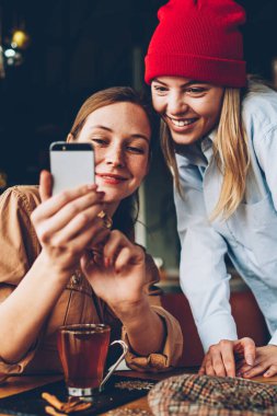 Neşeli iki hipsters smartphone aygıt komik video online izleme bağlı 4 g için Internet. Pozitif gençler sosyal ağlar üzerinde cep telefonu birlikte dinlenme kafe iç kontrol