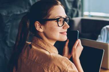 Uzak tutma smartphone elinde seyir ve modern netbook aygıt meslektaşım Smartphone'da söz ederken çalışan mutlu esmer öğrenci. Dizüstü bilgisayarlar kapalı oturan iki kadın serbest