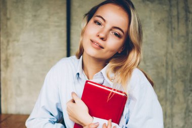 Not Defteri'nde eller liiking alan coworking içinde boş ekran alanı ile dijital netbook otururken kamera ile çekici sarışın hipster öğrenci portresi. Ders kitabı olan güzel kadın
