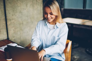 Kablosuz internet kullanarak Web sitesinde online arkadaşıyla sohbet mutlu sarışın kadın serbest meslek modern netbook için bağlı. Uzaktan coworking dizüstü bilgisayarda çalışan başarılı grafik tasarımcı