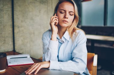 Ciddi hipster öğrenci kafede otururken smartphone aygıtında için işlecini çağırmak. Dalgın genç kadın dikkatle dinleme sesli mesaj kafede oturan telefonu operatörünüzden