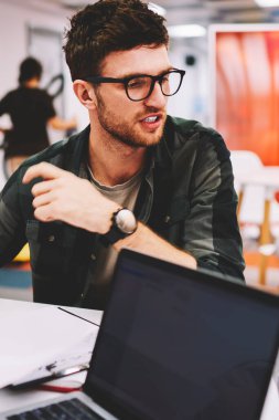 Gözlük vizyon düzeltme uzak ofis profesyonelleri ekip çalışma başlangıç geliştirmek için fikirleri tartışırken seyir için yetenekli erkek tasarımcısında. Beyin fırtınası sırasında konuşan zeki öğrenci