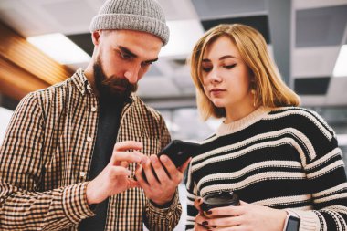 Dalgın sakallı hippi adam kadın blogger Smartphone'da 4 g internet bağlantısı ayarlarını yapma. İki öğrenci kahve molası ayakta Üniversitesi'nde sırasında online eğitsel cep telefonu izlemek