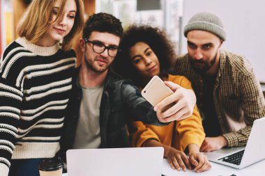Genç takım yaratıcı çok kültürlü öğrenci Üniversitesi'nde mola sırasında modern smartphone ön kamera üzerinde fotoğraf yapma. Cep telefonu dizüstü bilgisayarlar oturan selfies alarak rahat giyinmiş hipster çocuklar