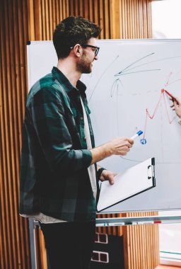 Planı düzeni eğitim oturumu başarılı erkek Koç Üniversitesi'nde tarafından yürütülmesi sırasında flipchart üzerinde yazma akıllı genç kadın. Profesyonel öğretmen gemide hipster öğrenci tarafından çizilmiş grafik denetimi