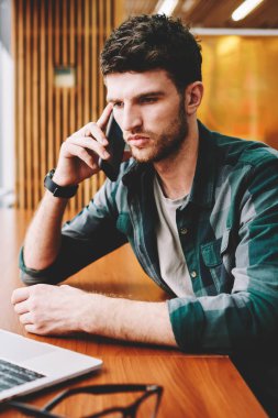 Mobil uygulama ile smartphone üzerinde Web sitesi video izlerken konuşmayı genç yakışıklı erkek Tasarımcısı. Modern cep telefonundan bilgi denetleme sırasında konuşan sakallı adam durulması