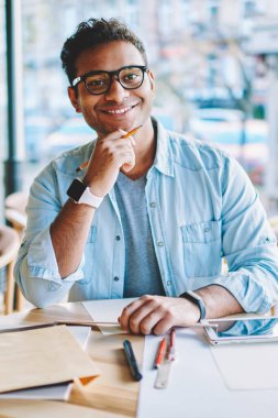 Yarım uzunluk portre serin gözlük rahat kafeteryada çalışan yakışıklı zeki gülümseyen erkek mimar. Yeni başlangıç projesi kapalı oluşturulurken kameraya bakarak olgun pozitif işadamı