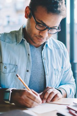 Kırpılmış görüntü yakışıklı zeki erkek mimar skeçler kalem ve cetvel kullanarak kağıt üzerine çizim şık kot elbise giymiş. Bazı bilgiler kapalı ölçme akıllı hipster adam durulması