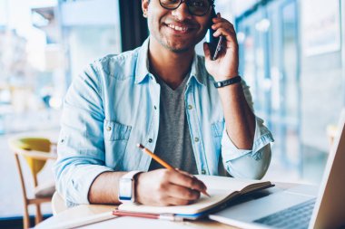 Mobil istemci ile 4 g için bağlı telefonda konuşmayı gülümseyen profesyonel Freelancer yarım uzunluk portre. Arkadaşlarınızla konuşurken ve Not defteri bilgileri kaydetmek mutlu erkek kişi