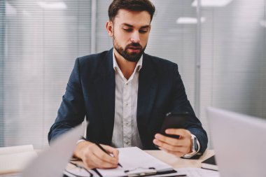 Dalgın gurur CEO'su bilgisi verilerini office iç çalışma smartphone aygıtından yeniden yazma. Sakallı işadamı muhasebe raporları yaparken gelen bildirim telefon üzerinde okuma