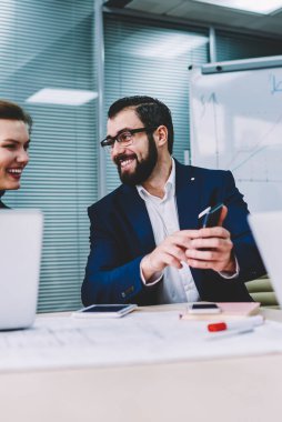 Genç yakışıklı gülümseyen grafik tasarımcı web sayfasında Smartphone cep telefonu ile komik video izlerken çekici kadın meslektaşı ile. Neşeli arkadaşları saygılarımla cep internet sitesinde haber okurken gülmekten