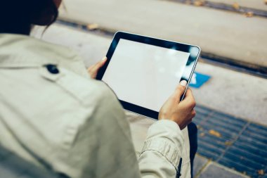 Arkadan Görünüş genç kadının okuma Rehberi aygıtındaki dijital dokunmatik ped boş ekran web sitenizin içeriği için indirilebilir. Arkadan görünüşü hippi kız eller alanında modern tablet sahte ile gidiyor