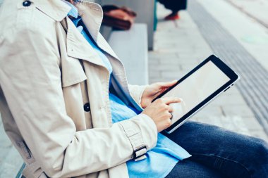 Tramvay durağı üzerinde oturan 4 g internet bağlantısı ile modern tablet medya dosyalarını seçerek şık genç kadın yan görünüm kırpılmış. Beyaz kadın dijital dokunmatik yüzey boş ekranda metin yazma