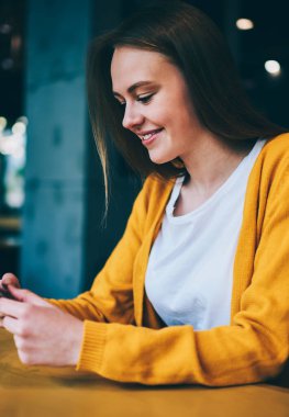 Mutlu hippi kız akıllı telefon cihazıyla internette geziniyor kafede oturuyor, başarılı kadın sosyal ağlarda arkadaşlarıyla sohbet ederken cep telefonunda ücretsiz kablosuz bağlantı kullanıyor.