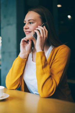 Kafeteryada kafein içeceğiyle dinlenen ve akıllı telefon aracılığıyla arkadaşlarıyla konuşan, dijital cep telefonuyla konuşan, komik hippi kız kafenin içinde yüksek hızlı mobil bağlantı kullanıyor.