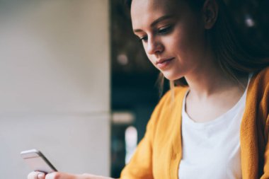 Akıllı telefondan mesaj gönderen konsantre bir kız öğrenci dizüstü bilgisayarla aynı masada oturuyor ve kafeterya kablosuz internete bağlanıyor. Ciddi bir kadın yeni telefon ihbarnamesini güncelliyor.