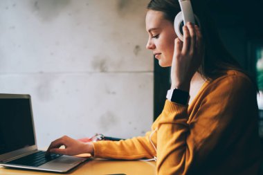 Kulaklıklı beyaz yeniyetme kız laptopta mesaj yazıyor. Reklam metinleri için alan hazırlıyor. Kafeteryada netbook üzerinde çalışırken kulaklıkla kitap dinlemekten hoşlanan genç bir kadın.