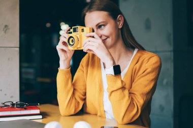 Klasik fotoğraf makinesine odaklanan, kapalı mekanda fotoğraf çeken, eski moda ekipmanlarla fotoğraf çeken ve kafeteryada hoppala eğlenen pozitif hippi kız.