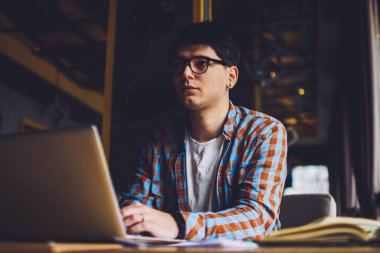 Macbook bilgisayarının başında oturan düşünceli blogcu kendi web sitesini kurmak için ilginç fikirler düşünüyor. Dizüstü bilgisayarda okuyan ve yaklaşan sınavlara hazırlanan genç adam.