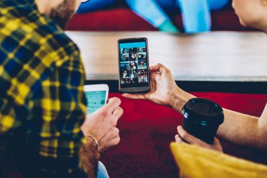 Modern akıllı telefon cihazında canlı yayın yapan sıradan giyinmiş gençlerin arka plandaki görüntülerini kestim. Günlük giyinmiş arkadaşlar web sitesinde 4G internet bağlantısını kullanarak medyayı izliyorlar.