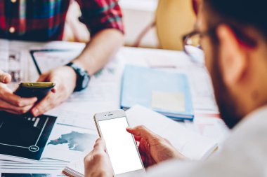 İnternet içeriğiniz için boş ekran alanı olan modern akıllı telefona mobil uygulama yükleyen genç bir adamın arka görüntüsü. Hipster adam telefon tutan ve internet üzerinden sohbet eden biri.