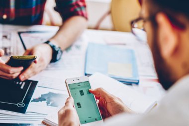 Wireless 4G internetini kullanarak modern akıllı telefona mobil uygulama yüklemek için yazılım güncelleyen genç adamın arka görüntüsü kesildi. Hipster adam elinde telefonla takipçilerle çevrimiçi sohbet ediyor.