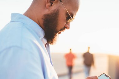 Genç yakışıklı adam sokakta, uygulama ayakta bankacılık yoluyla işlem yapma smartphone posta denetleme ve sosyal ağları kullanarak hücresel göndermesini görünümü erkek hipster yakın