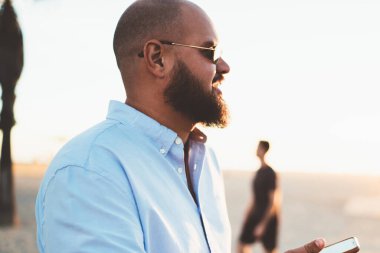 Sakallı adam cep telefonu online sosyal ağlar tatilden gezici pay fotoğraf 4 g bağlantısında hipster adam memnun yaz akşamında, tadını çıkarırken sohbet üzerinden kısa mesaj gönderme