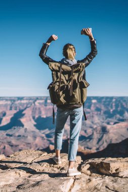 Arkadan görünüşü kadın turist sırt çantası duygu özgürlükle macera Büyük Kanyon parkta sahip cliff üzerinde ayakta eller yukarı, hippi kız Yolculuk tutkusu yükselterek dağın tepesinde almak zaferini kutluyor