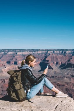 Milli Park, dağ tepe üzerinde yürüyüş sırasında hücresel dinlenme üstünde posta kontrol kadın turist Yolculuk tutkusu kayalık uçurum üzerinden ileti göndermek için mobil bağlantı kullanarak sırt çantası ile gülümseyen kız