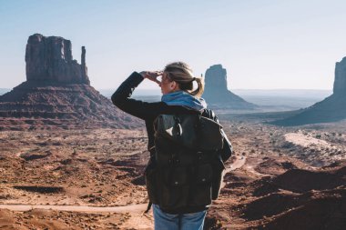 Arkadan görünüşü kadın turist Monument valley hippi kız Milli Parkı yüksek kumtaşı oluşumu seyir hiking sırt çantası ile ABD, güney batısında keşfetmek güzel manzara gözlem