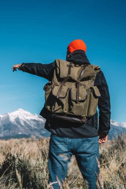 Dağ en iyi yürüyüş gezisi sırasında uzak güzel ABD doğa keşfetmek hipster adam Yolculuk tutkusu gösteren yüksek karlı zirveleri elini içeri planlamayla ilgili konuya işaret eden sırt çantası ile erkek Gezgin görünümünü geri
