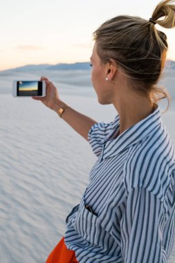 Hippi kız cep telefonu ünlü Amerikan dönüm noktası beyaz ziyaret resim yapma tutan kumları Park batımında, arkadan görünüşü doğal Doğa manzara fotoğraflarını smartphone kamera çekimi kullanan genç kadın