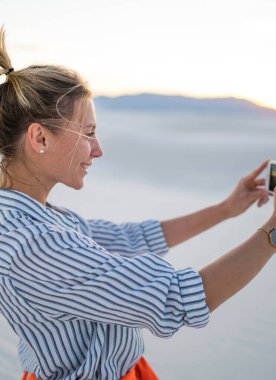 Hippi kız manzara resmini alarak poz selfie smartphone ayakta beyaz kumları Milli Parkı'nda, tarih için genç blogger gülümseyen güzel doğa Yolculuk tutkusu yaz tatillerini zevk gezisi sırasında