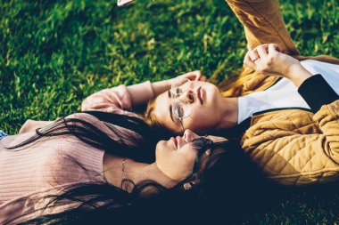 İki en iyi arkadaş blogcular park yeşil çim üzerinde yalan ve Rekreasyon zaman güneşli havalarda sırasında modern smartphone aygıt kendi web sitesi için ön kamera fotoğraf yapma şık güneş gözlüğü