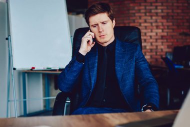 Ciddi bir erkek yöneticinin, telefon görüşmesi sırasında iş arkadaşına danışması, konsantre iş adamı, operatör çek hesabı bakiyesi ile ciddi bir akıllı telefon görüşmesi yapıyor.