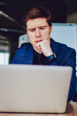 Şaşkın erkek çalışan önemli web sitelerini izlerken ders kitabında ana bilgileri yazarken, düşünceli beyaz girişimci sosyal ağlarda haberleri okurken modern netbook 'ta 4G bağlantısı kullanıyor.