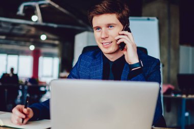 Pozitif iş adamı ofisinde otururken arkadaşını arıyor ve ders kitabına bir şey not ediyor, Kafkas erkek patronu akıllı telefon cihazıyla 4G internet kullanarak iletişim kuruyor.